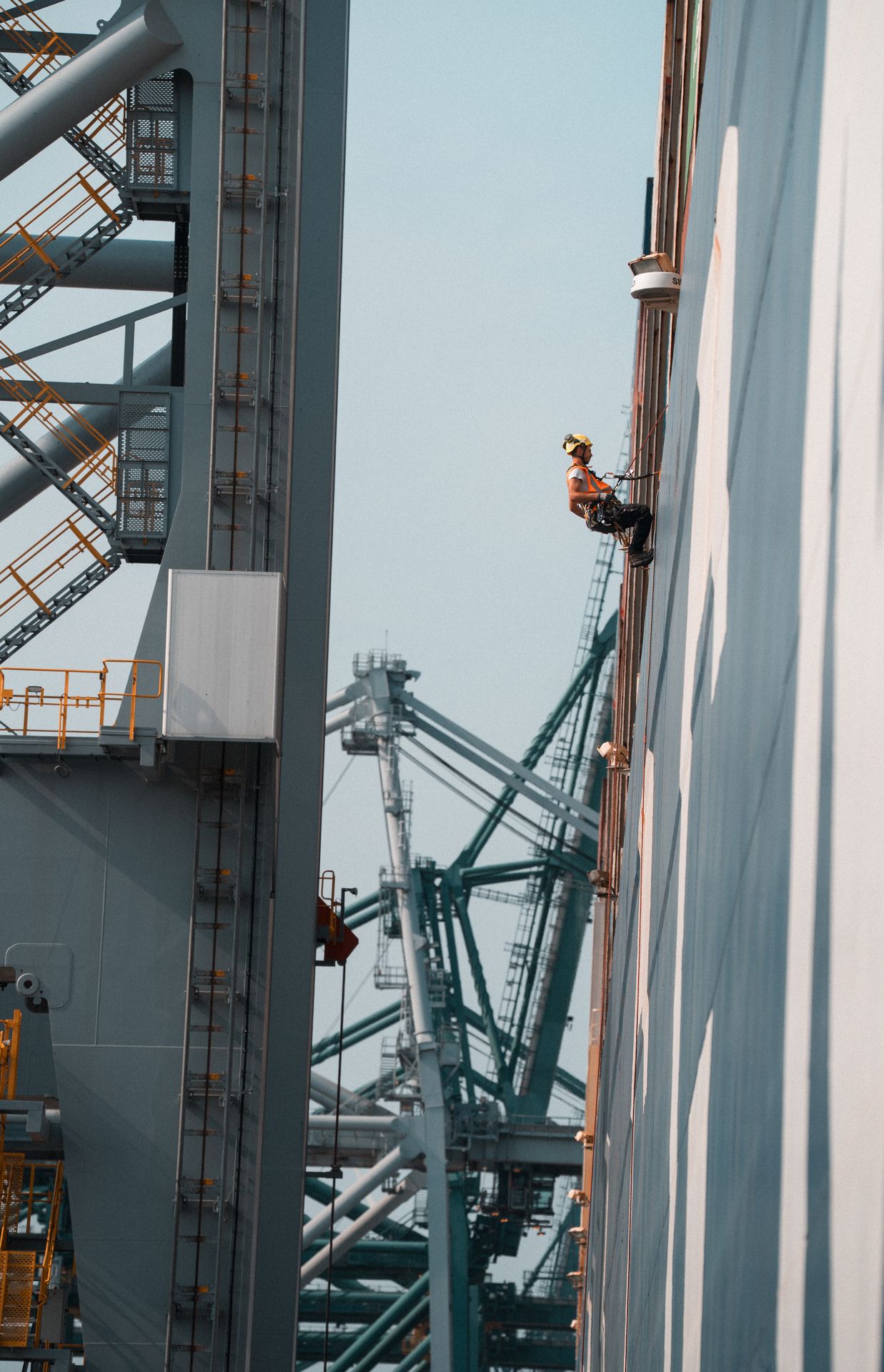 Cordiste en intervention de maintenance sur une structure industrielle métallique de grande hauteur.