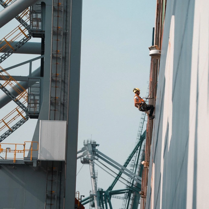 Cordiste en intervention de maintenance sur une structure industrielle métallique de grande hauteur.