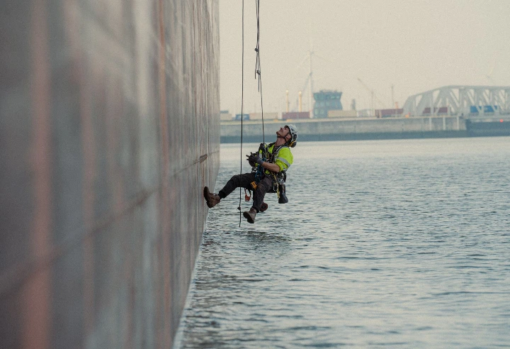 Technicien cordiste en intervention de maintenance sur une structure industrielle située au-dessus de l&#39;eau dans une zone portuaire