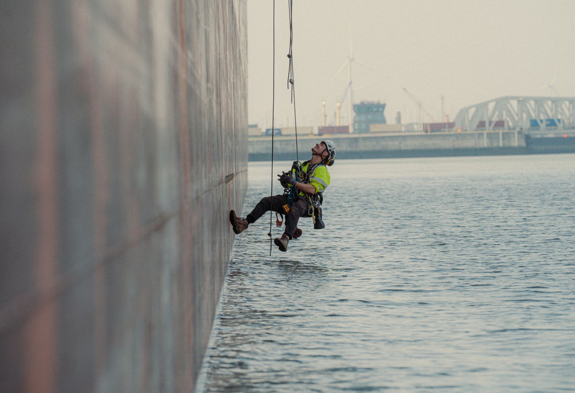 Technicien cordiste en intervention de maintenance sur une structure industrielle située au-dessus de l&amp;#39;eau dans une zone portuaire