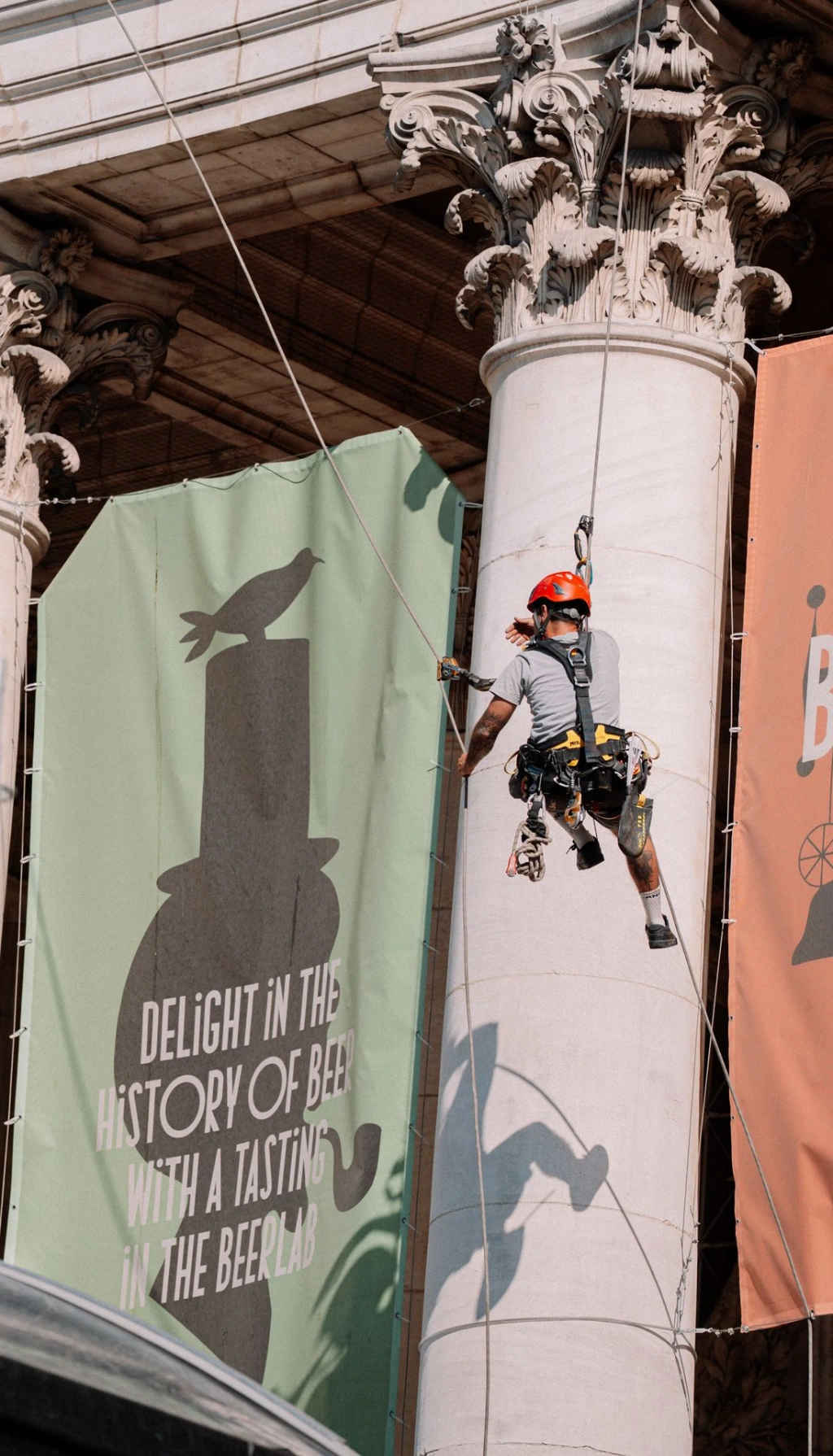 Cordiste réalisant la mise en place de bâches publicitaires sur la Bourse en accès difficile à Bruxelles