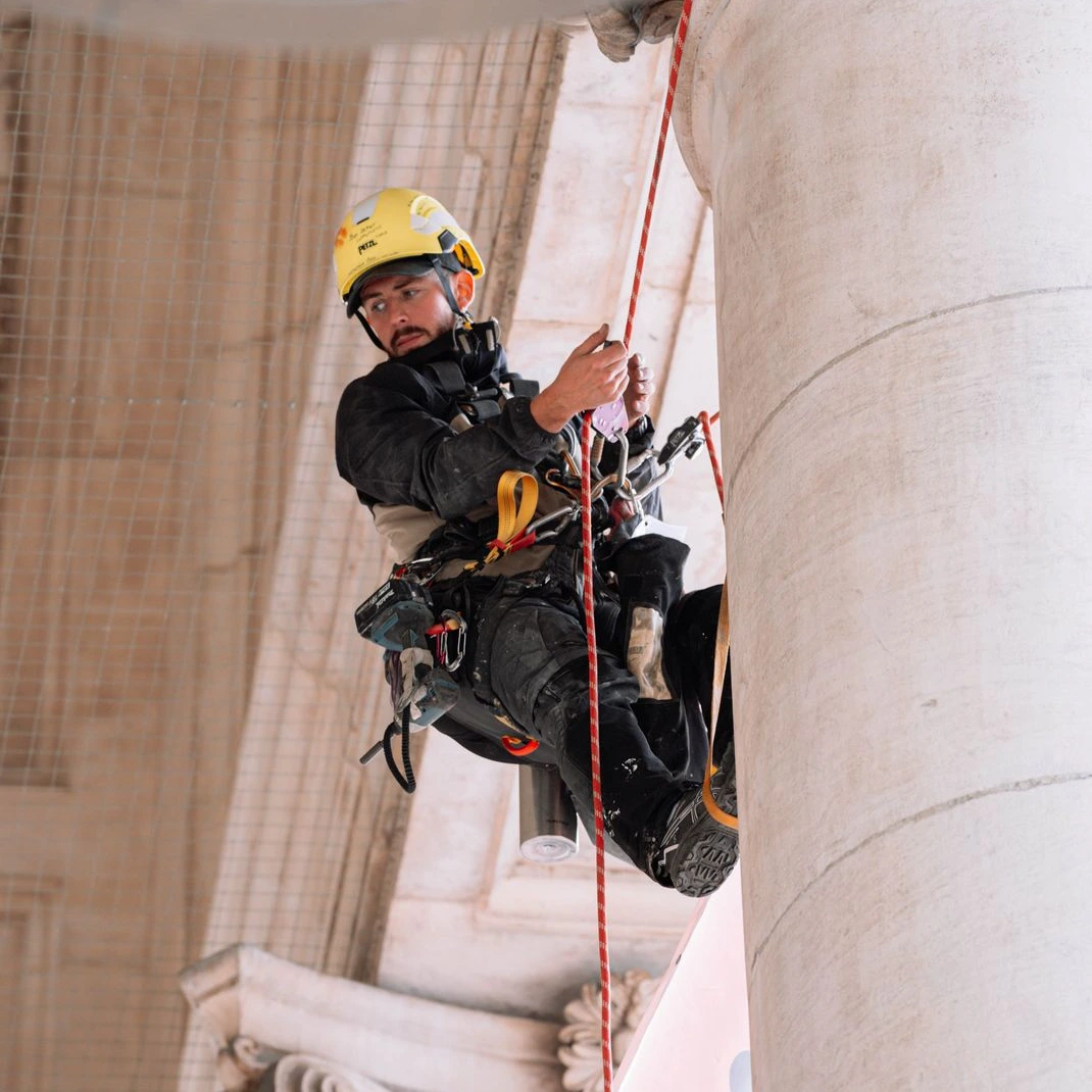 Cordiste réalisant la mise en place de bâches publicitaires sur la Bourse en accès difficile à Bruxelles