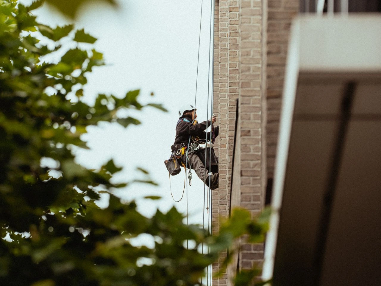 Cordiste réalisant la réfection des joints souples d'un immeuble de bureau en accès difficile à Etterbeek