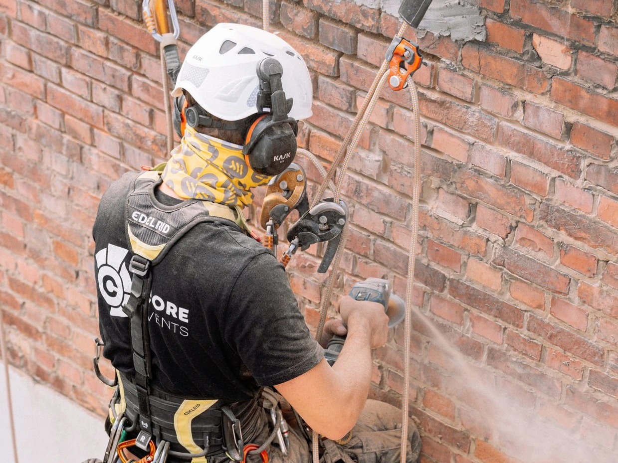 Cordiste réalisant des travaux de maçonnerie d'un immeuble en accès difficile à Forest