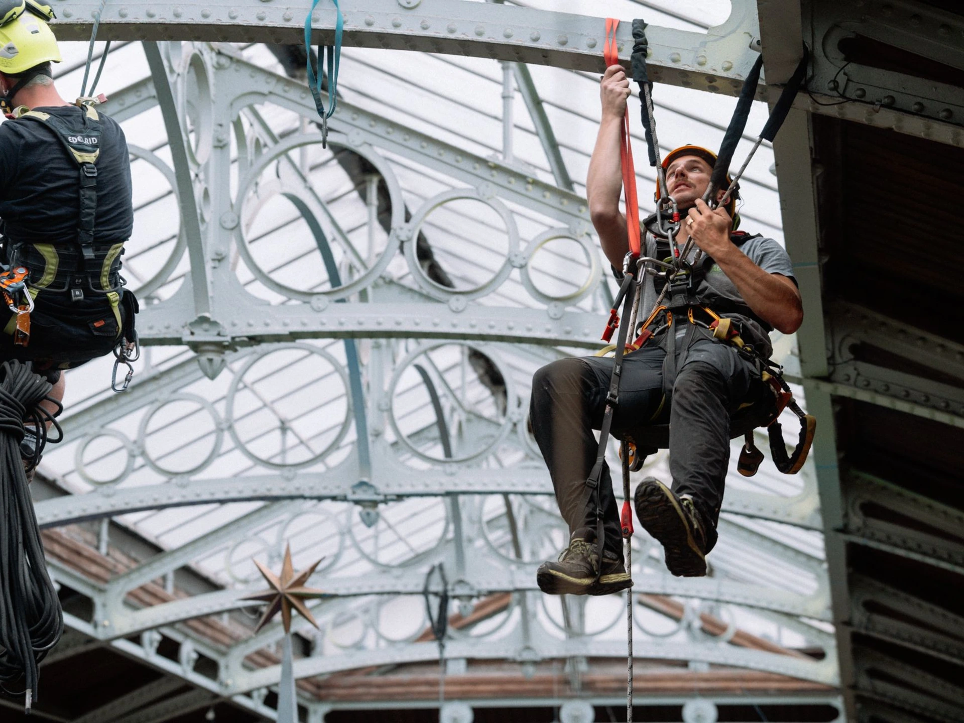 Cordiste mettant en place des éléments décoratifs dans les Halles Saint-Géry en accès difficile à Bruxelles pour Philippe Katerine - Exposition Monsieur Rose
