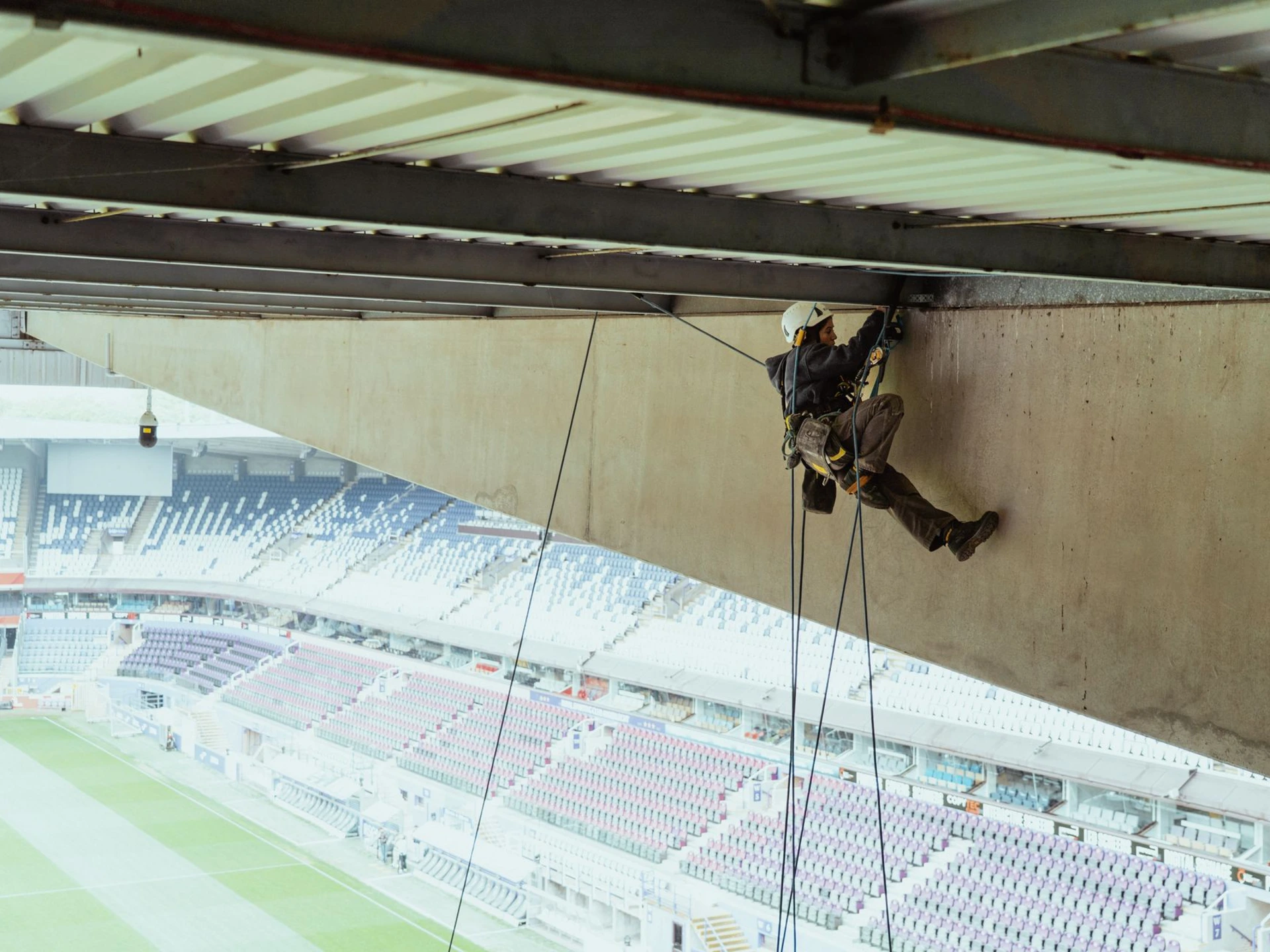 Cordiste réalisant des travaux de sécurisation des tribunes du stade de football Lotto Park en accès difficile à Anderlecht