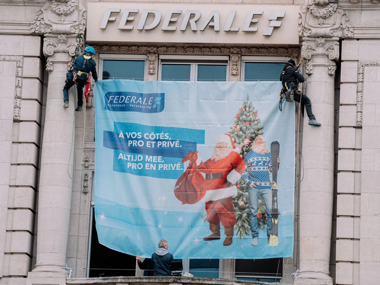 Cordiste mettant en place une bâche publicitaire sur un immeuble en accès difficile à Bruxelles