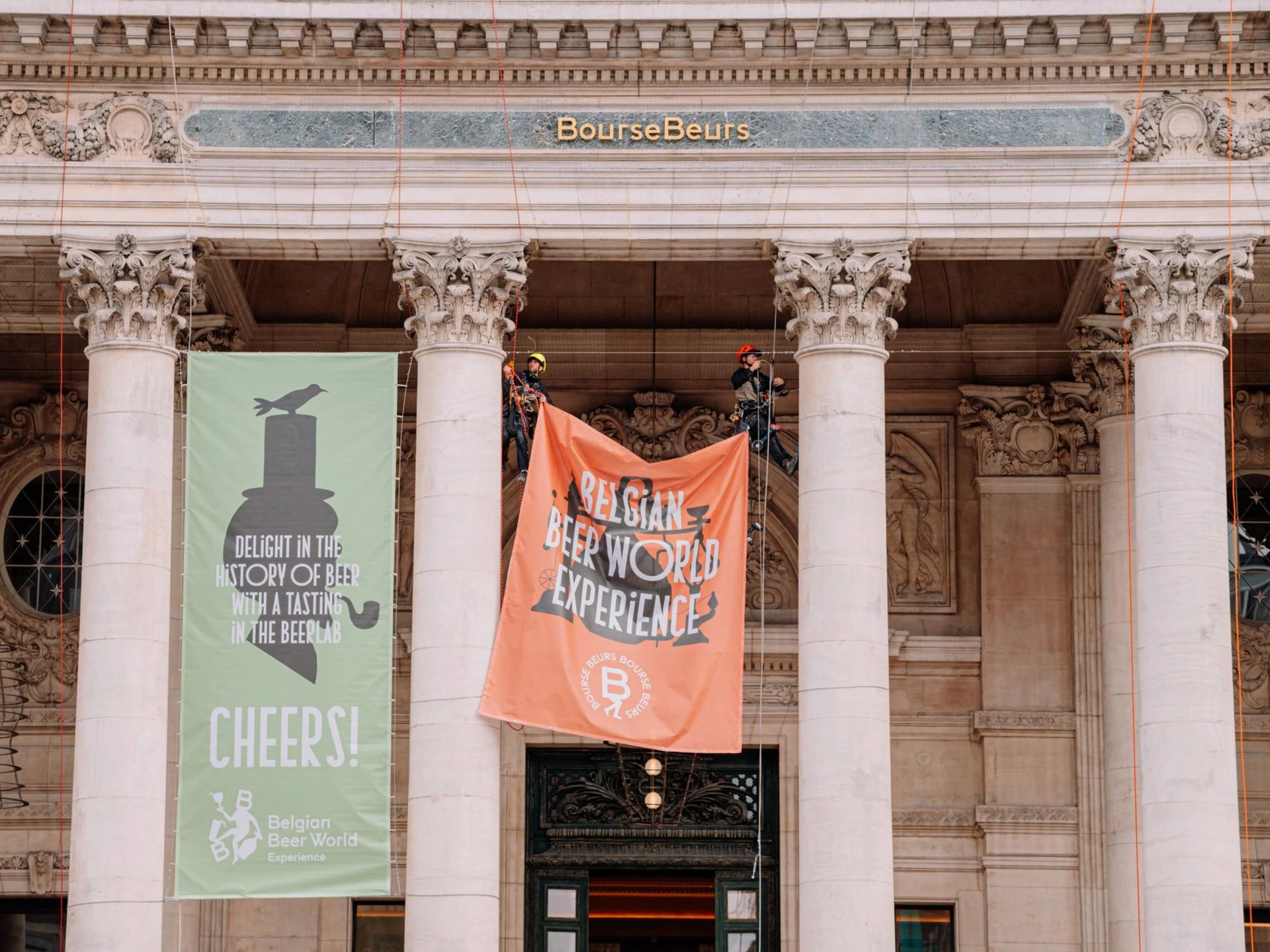 Cordiste mettant en place une bâche publicitaire sur la Bourse en accès difficile à Bruxelles