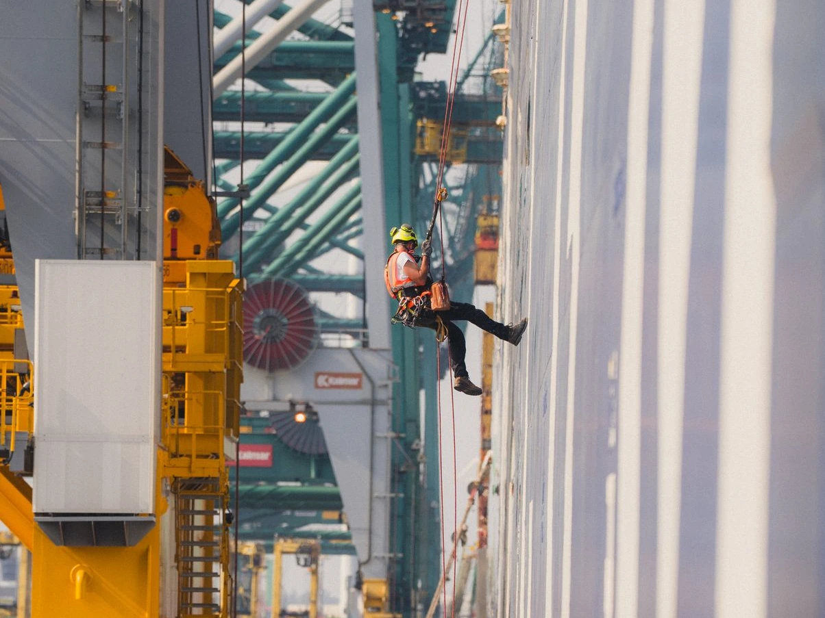 Cordiste réalisant la remise en peintre de la coque d'un porte-container en accès difficile au Port d'Anvers